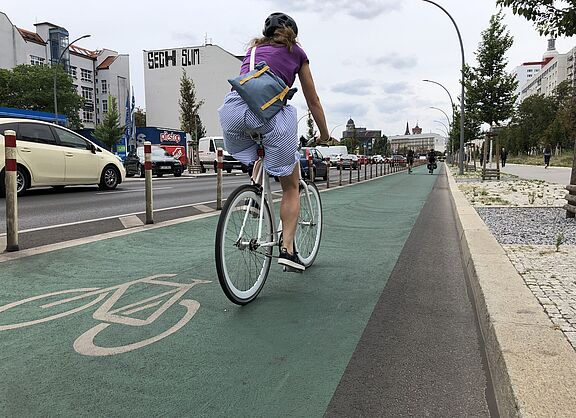 Frau auf geschütztem Radfahrstreifen Frau auf geschütztem Radfahrstreifen